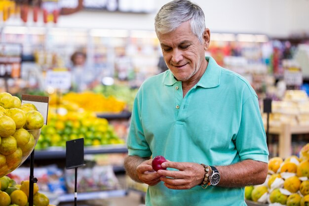 Handsome man posing, looking at camera and holding melon in hand. bearded customer smiling. section with fresh citruses on space