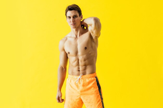 Handsome man posing in studio wearing beach trunks.