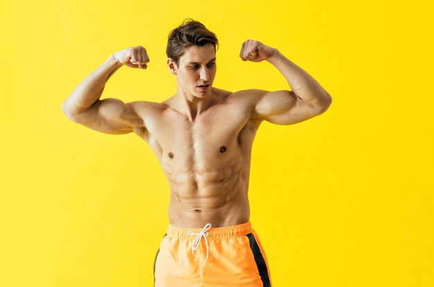 Handsome man posing in studio wearing beach trunks.