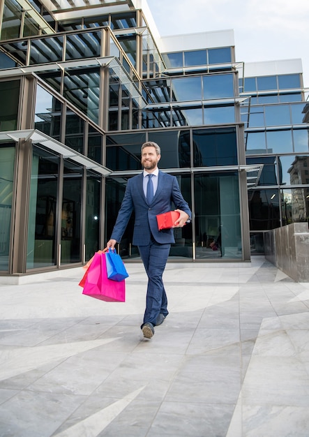 Un bell'uomo si prepara per un appuntamento romantico. uomo d'affari felice cammina all'aperto con ricompensa di affari. occasione di saluto. manager tenere presente aziendale. regalo per la festa della donna. ceo di successo con confezioni regalo