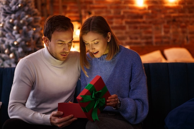 Handsome man presenting a gift to his beautiful wife and smiling.