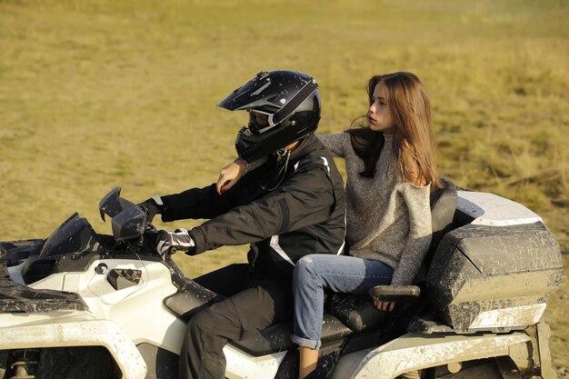 Photo handsome man and pretty girl ride quad bike on field road on natural background