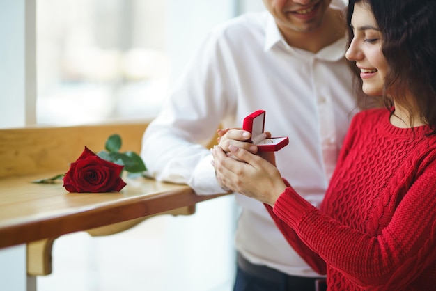 Handsome man proposing a beautiful woman to marry him in restaurant Valentines day concept