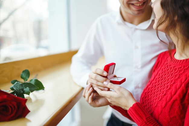 Handsome man proposing a beautiful woman to marry him in restaurant Valentines day concept