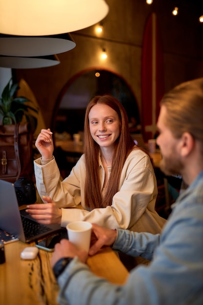 Bell'uomo e donna dai capelli rossi che discutono di progetti di business al bar mentre bevono un caffè. nella caffetteria accogliente. avvio, idee e concetto di tempesta di cervello. vista laterale. copia spazio