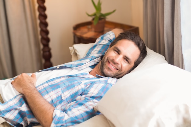 Handsome man relaxing on his bed reading magazine