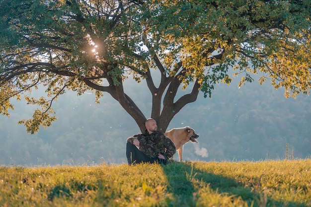 A handsome man resting after walks with a dog on the autumn forest