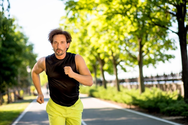 Handsome man running outdoors at full speed. Sexy brunette in sports clothes dreaming abour getting perfect body.