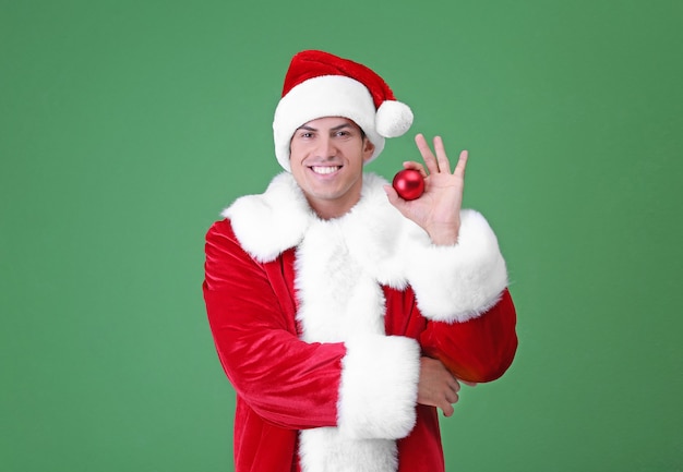 Handsome man in Santa Claus costume holding shiny bauble