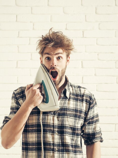 Photo handsome man screams with iron