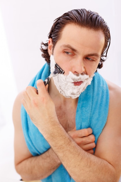 Handsome man shaving in bathroom