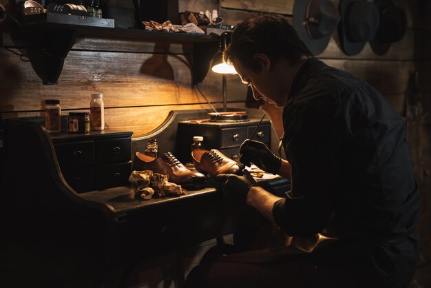 Handsome man shoemaker at footwear workshop.