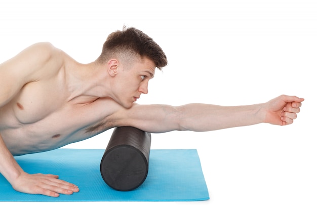 Handsome man shows exercises using a foam roller