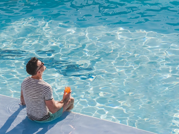 Handsome man sits near the swimming pool