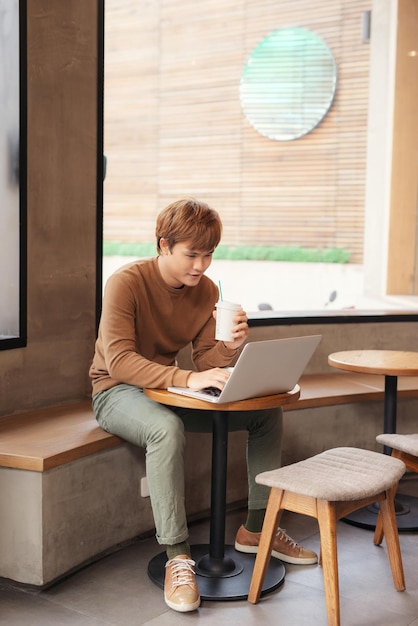 Handsome man sitting alone at table in coffee shop cafe working