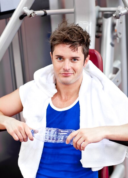 Handsome man sitting on a bench press  after exercises