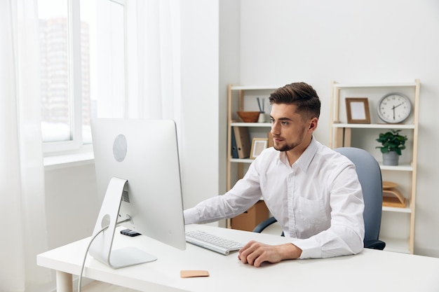 Handsome man sitting at a desk in front of a computer with a\
keyboard executive