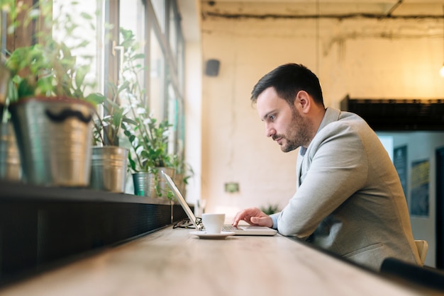 Handsome man sitting front of laptop in the cafe.