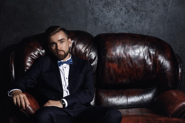 Photo handsome man sitting on the leather sofa