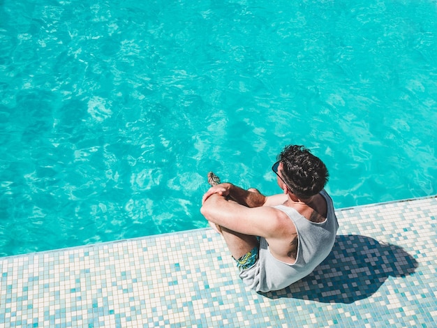 화창한 아침 맑은 날 유람선의 수영장 근처에 앉아 있는 잘생긴 남자 위에서 본 근접 촬영 야외 휴가 및 여행 개념
