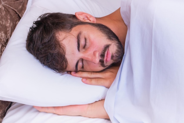 Handsome man sleeping in bed with a comfortable pillow. Portrait of a man sleeping in bed at home