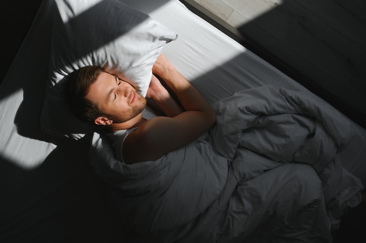 Photo handsome man sleeping under soft blanket in bed at home