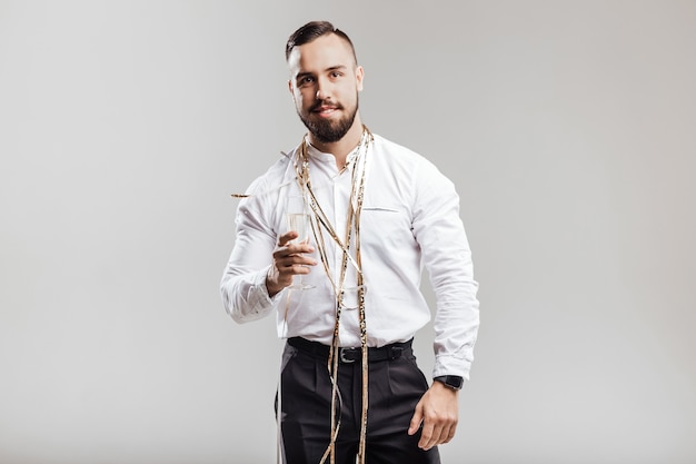 Handsome man smiles and holds glass of champagne on a white background. Party time .