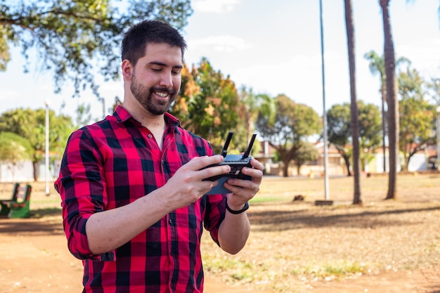 Handsome man in the square piloting a drone. Young boy with the remote control filming with the drone.