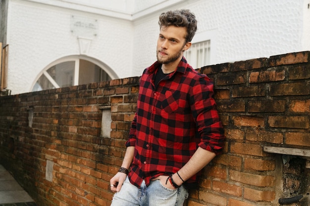 Photo handsome man standing against brick wall