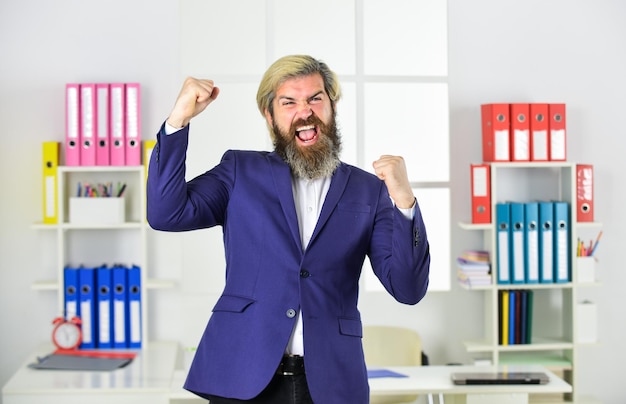 Красивый мужчина, стоящий и выражающий счастье Портрет бизнесмена, стоящего в офисе