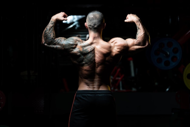 Handsome Man Standing Strong In The Gym And Flexing Muscles Muscular Athletic Bodybuilder Fitness Model Posing After Exercises