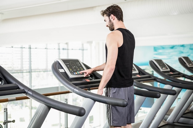 Handsome man standing on treadmill at the gym