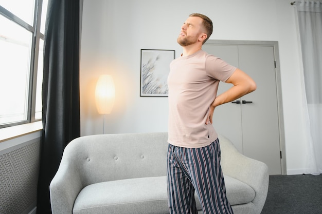 Handsome man suffering from backache at home