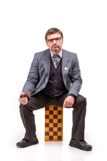 A handsome man in a suit and glasses with chess and a pipe for smoking White background