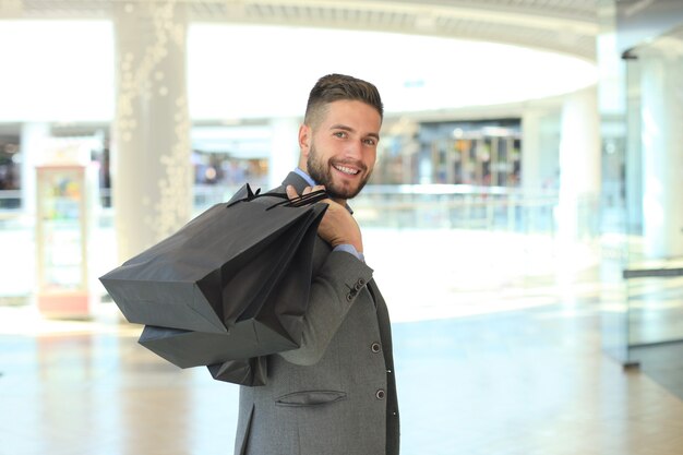 Handsome man in suit with shopping bags.