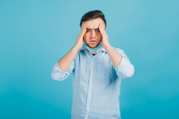 Handsome man touching his temples to calm a headache on blue background