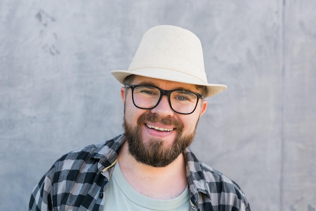 Handsome man tourist portrait looking happy wearing straw hat for travelling standing against concre