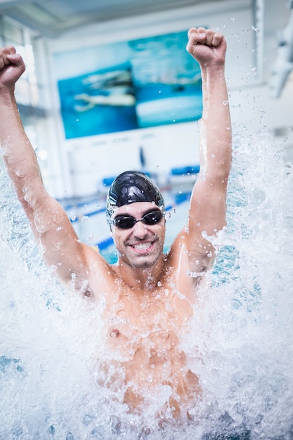 Handsome man triumphing in the water at the pool