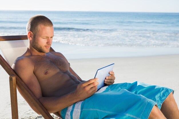 Photo handsome man using his tablet while sunbathing