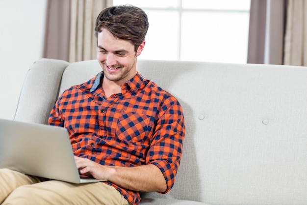 Handsome man using laptop on the couch in the living room 