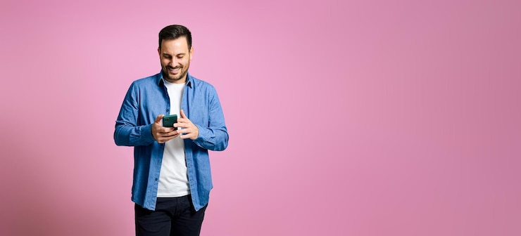 Photo handsome man using mobile phone over pink background