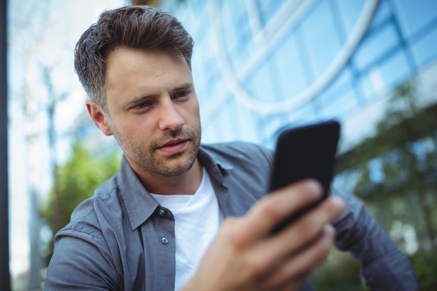 Uomo bello che per mezzo del telefono cellulare