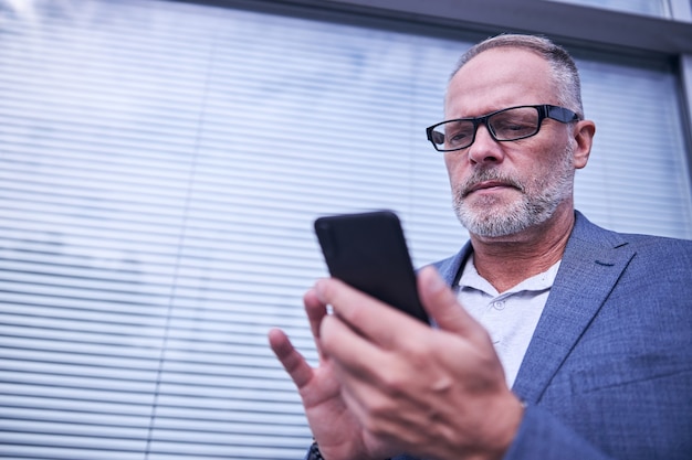 Bell'uomo che utilizza uno smartphone moderno per strada