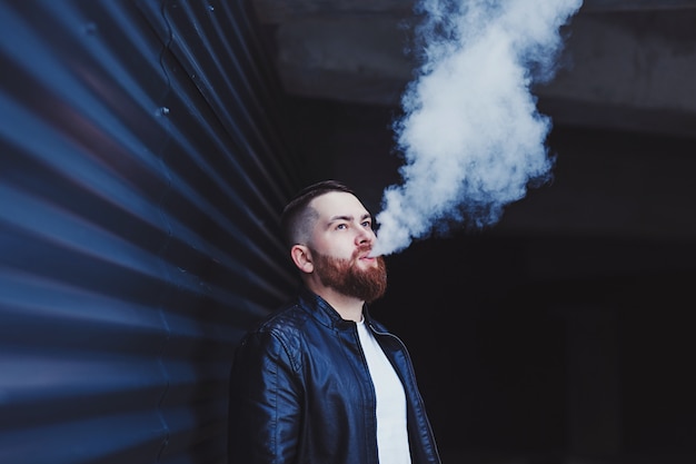 Foto uomo bello in uno svapo una sigaretta elettronica