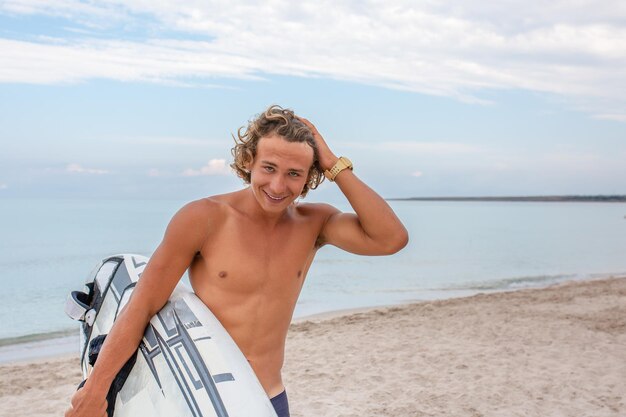 白い空白のサーフィンボードでハンサムな男が海の海岸でサーフィンスポットに波を待つスポーツフィットネス自由幸福の概念新しい現代生活ヒップスター