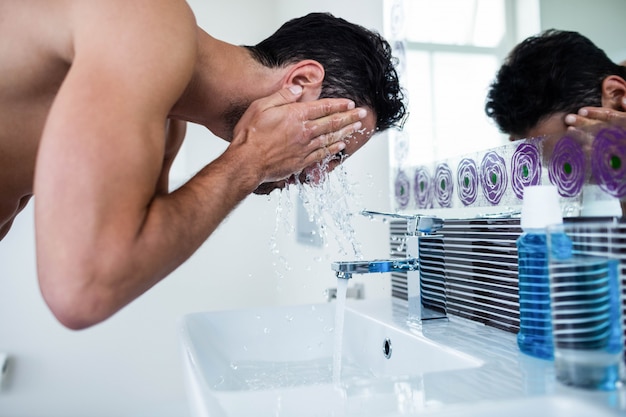 Handsome man washing his face in bathroom