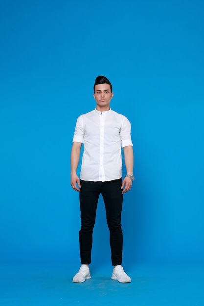 Handsome man wear black leather jacket. full length photo of a young casual man standing with his jacket on his shoulder and his hand in his pocket while looking into the camera. on blue background