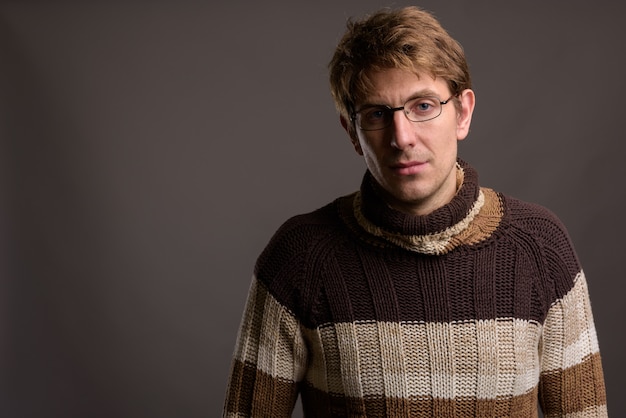 Handsome man wearing eyeglasses against gray wall