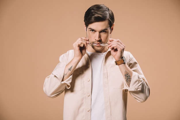 Handsome man wearing glasses isolated on beige