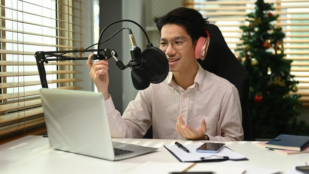 Handsome man wearing headphone recording podcast from home studio Radio podcasts blogging and technology concept